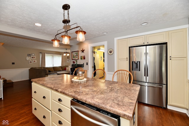 kitchen with cream cabinets, a kitchen island, dark hardwood / wood-style floors, and appliances with stainless steel finishes