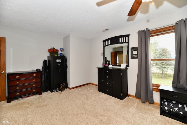 bedroom featuring a textured ceiling, light colored carpet, and ceiling fan