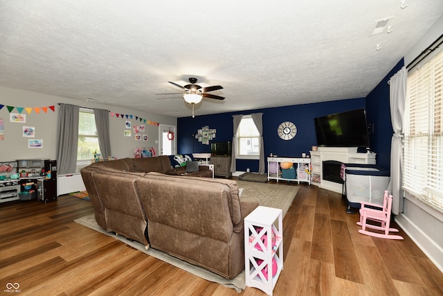 living room featuring a textured ceiling, hardwood / wood-style flooring, and ceiling fan