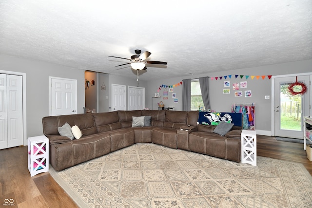 living room featuring wood-type flooring, ceiling fan, and a textured ceiling