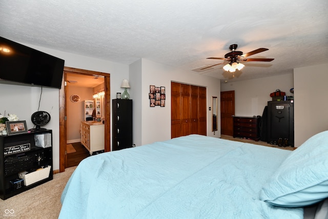 bedroom with carpet flooring, a textured ceiling, connected bathroom, ceiling fan, and a closet