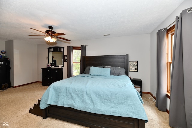 carpeted bedroom featuring ceiling fan and a textured ceiling