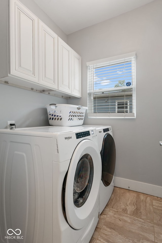 clothes washing area featuring cabinets and washer and dryer