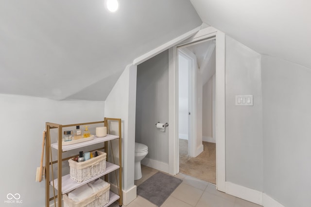 bathroom featuring tile patterned flooring, vaulted ceiling, and toilet