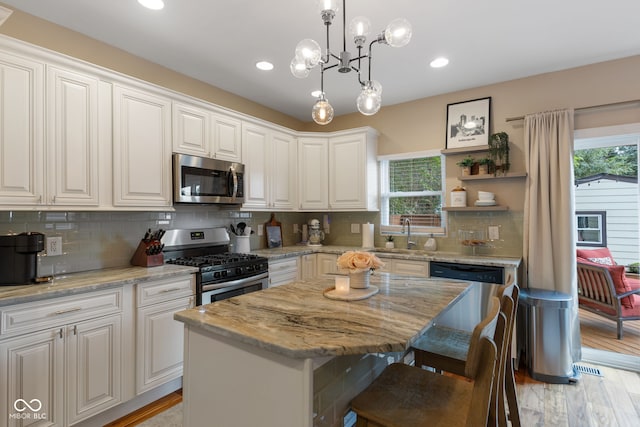 kitchen with light stone countertops, stainless steel appliances, white cabinets, and a kitchen island