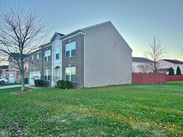 property exterior at dusk featuring a garage and a yard