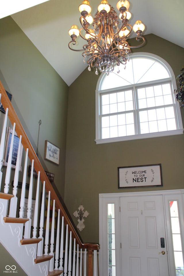 foyer featuring an inviting chandelier, high vaulted ceiling, and a wealth of natural light