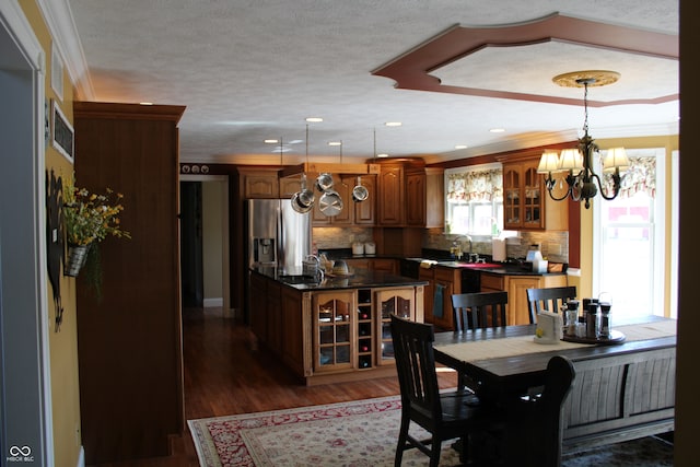 dining area featuring dark wood-type flooring, a textured ceiling, crown molding, sink, and a chandelier