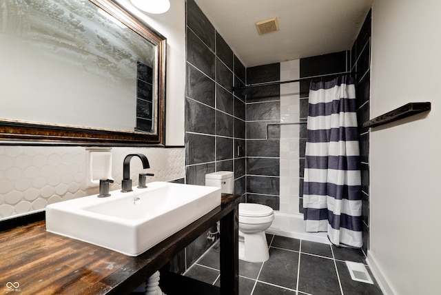 bathroom featuring toilet, tile patterned flooring, a shower with curtain, sink, and tile walls