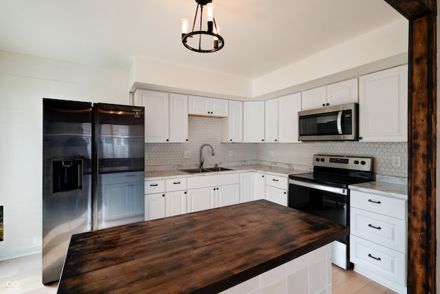 kitchen featuring sink, butcher block counters, white cabinetry, light hardwood / wood-style floors, and stainless steel appliances