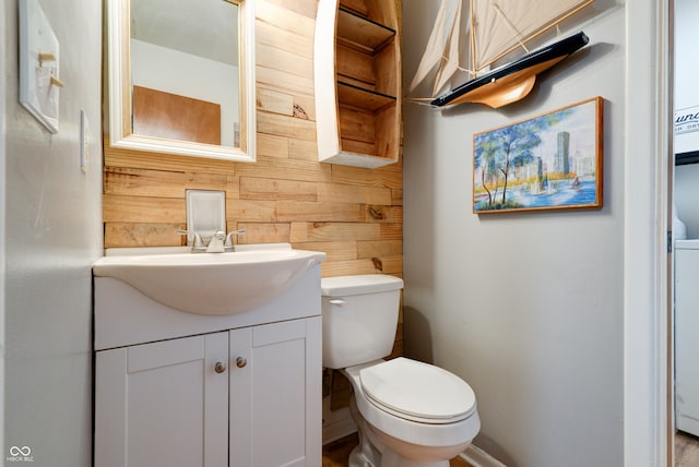 bathroom featuring vanity, toilet, and wood walls