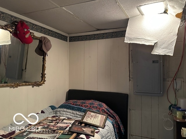 bedroom with wood walls and electric panel