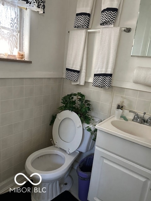 bathroom featuring vanity, tile walls, and toilet