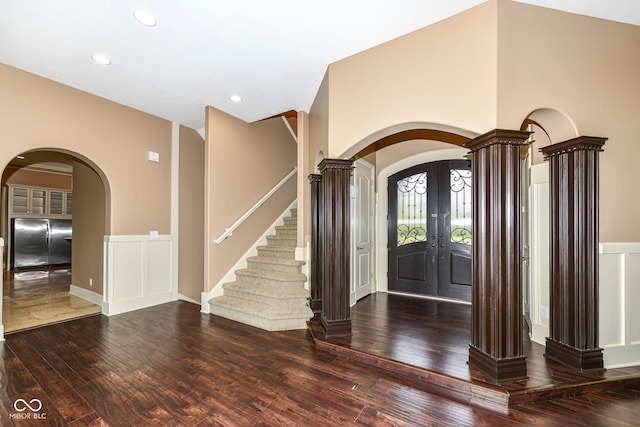 foyer entrance with wood-type flooring, french doors, and decorative columns