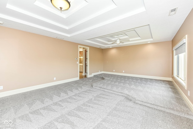 carpeted spare room with ceiling fan and a raised ceiling