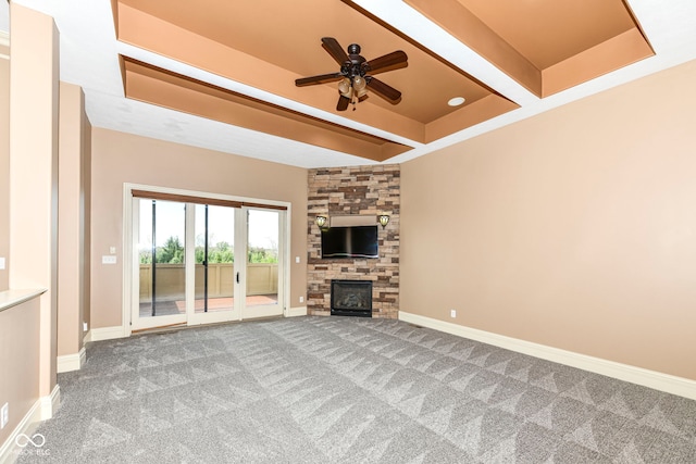 unfurnished living room featuring ceiling fan, a stone fireplace, and carpet