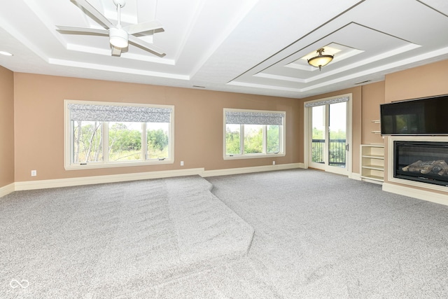 unfurnished living room with a raised ceiling, carpet, and ceiling fan