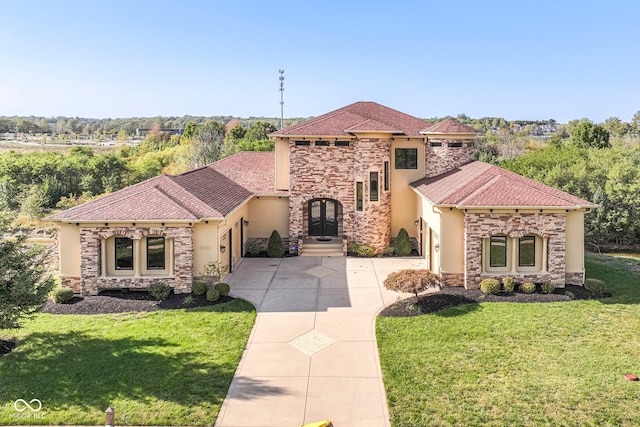 mediterranean / spanish home with stucco siding, concrete driveway, stone siding, a front yard, and a garage