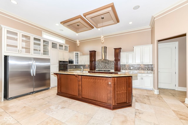 kitchen with wall chimney exhaust hood, decorative backsplash, a kitchen island with sink, and stainless steel appliances