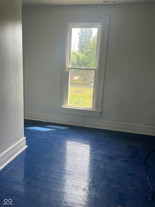 spare room featuring a wealth of natural light and dark hardwood / wood-style floors