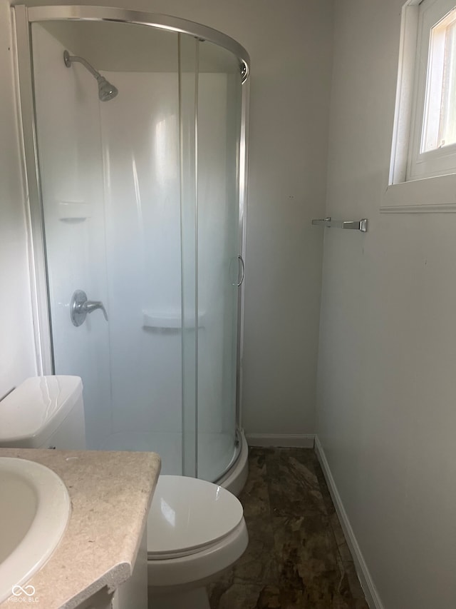 bathroom featuring vanity, toilet, and a shower with shower door