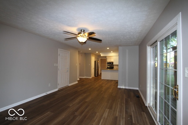 unfurnished living room with ceiling fan, dark hardwood / wood-style floors, and a textured ceiling