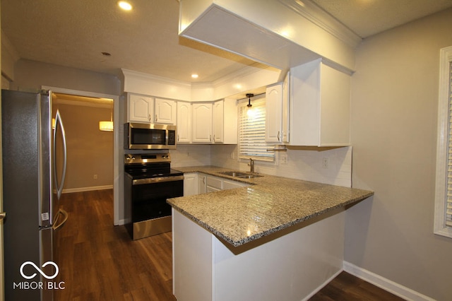 kitchen with light stone counters, stainless steel appliances, white cabinets, sink, and kitchen peninsula