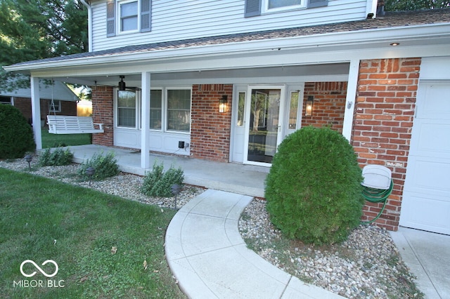 doorway to property with ceiling fan, a garage, and a porch