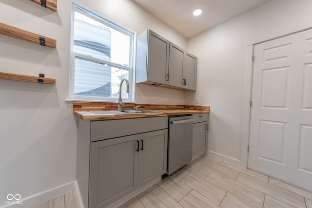 kitchen featuring gray cabinets, sink, wood counters, and stainless steel dishwasher