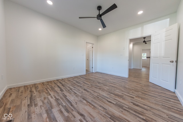 unfurnished bedroom with wood-type flooring, ceiling fan, and a walk in closet