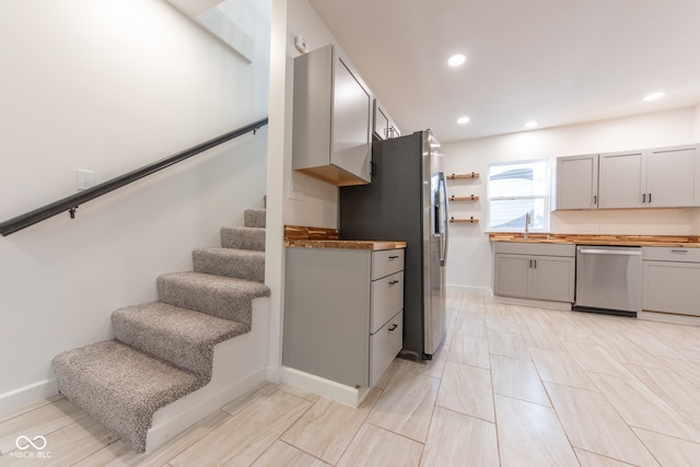 kitchen with gray cabinets, stainless steel appliances, sink, and butcher block counters