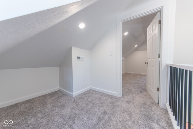 bonus room featuring light carpet, lofted ceiling, and a textured ceiling