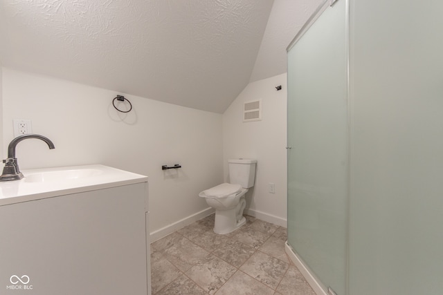 bathroom with vaulted ceiling, vanity, toilet, and a textured ceiling