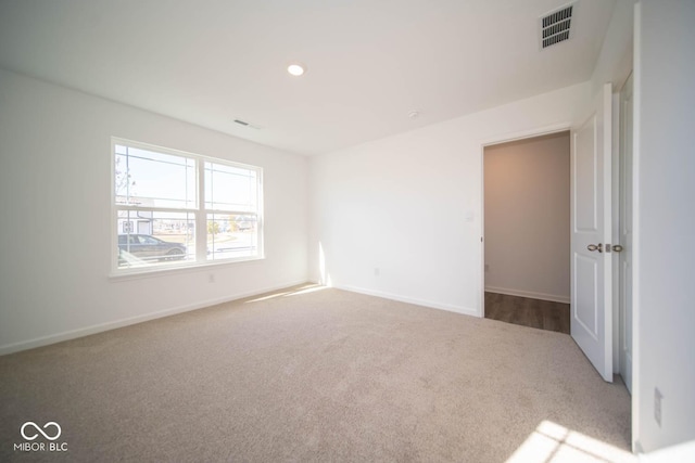 spare room with baseboards, visible vents, and carpet
