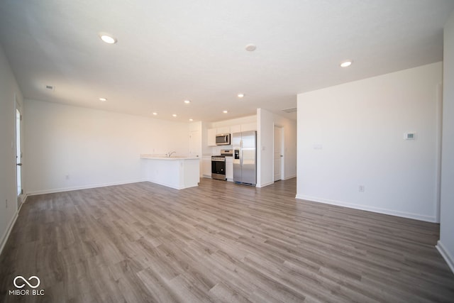 unfurnished living room featuring hardwood / wood-style flooring and sink