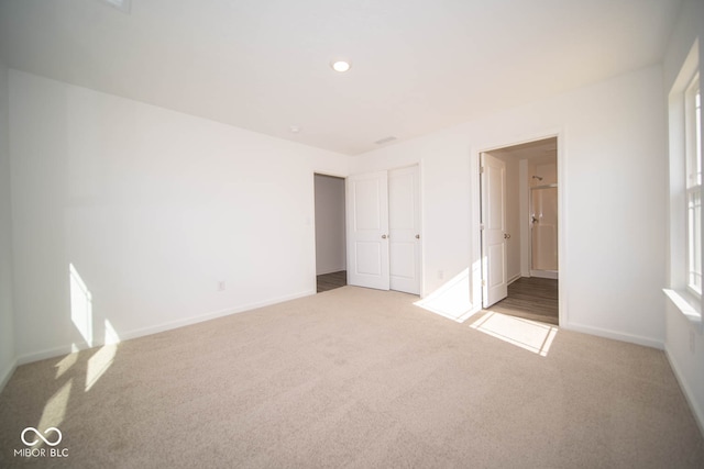 unfurnished bedroom featuring a closet and light colored carpet