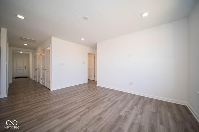 spare room with recessed lighting, visible vents, wood finished floors, and baseboards