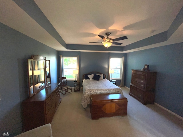 bedroom featuring ceiling fan, a raised ceiling, and multiple windows