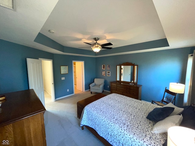 bedroom featuring ceiling fan, a raised ceiling, and light colored carpet