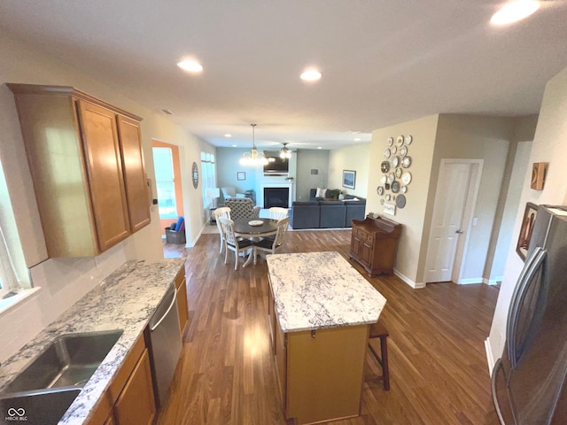 kitchen with appliances with stainless steel finishes, dark hardwood / wood-style floors, a kitchen breakfast bar, and a kitchen island