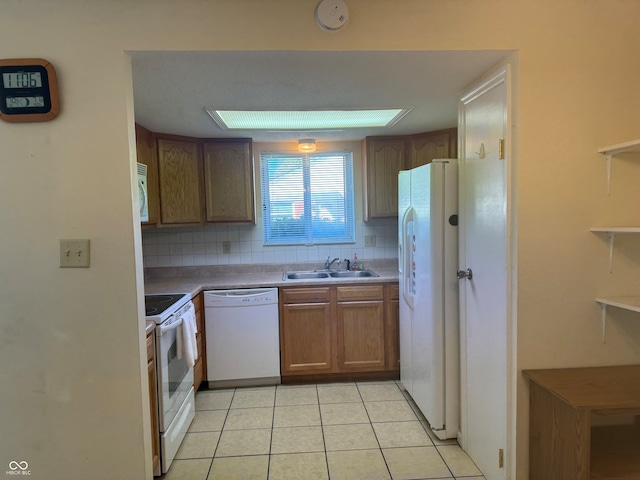 kitchen featuring light tile patterned floors, white appliances, tasteful backsplash, and sink