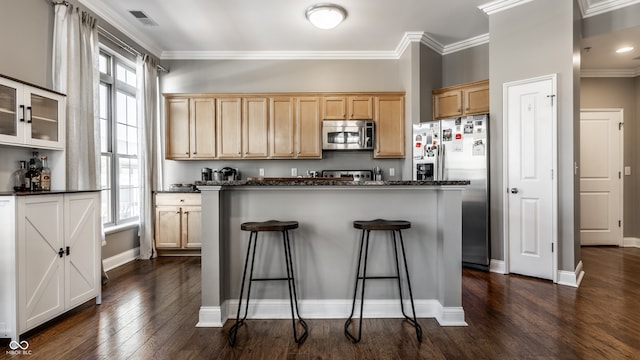 kitchen featuring dark hardwood / wood-style floors, crown molding, appliances with stainless steel finishes, and a center island