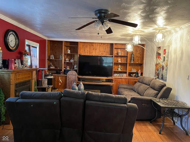 living room with crown molding, built in features, light wood-type flooring, and ceiling fan