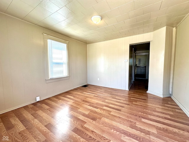 empty room with wood walls and light hardwood / wood-style floors