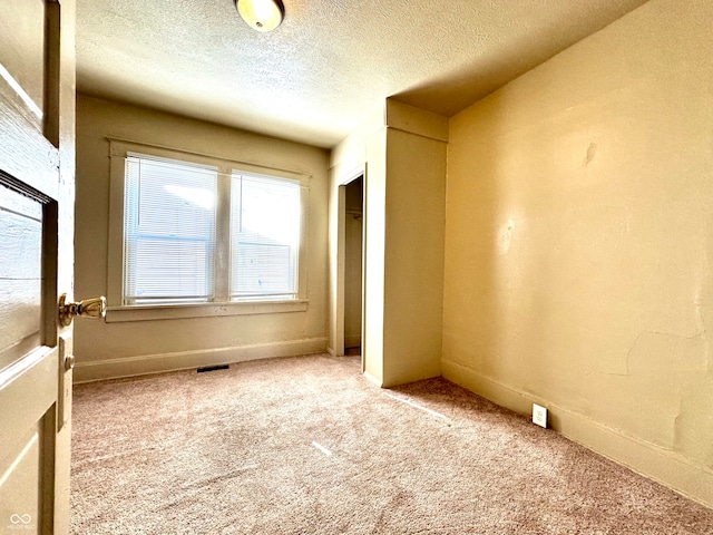 unfurnished room featuring carpet floors and a textured ceiling