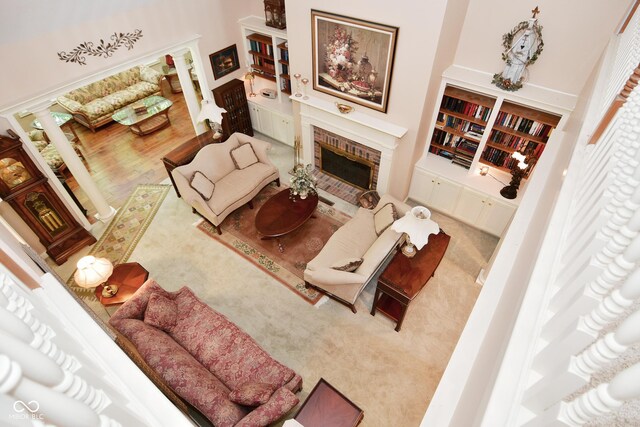 carpeted living room featuring decorative columns and a brick fireplace