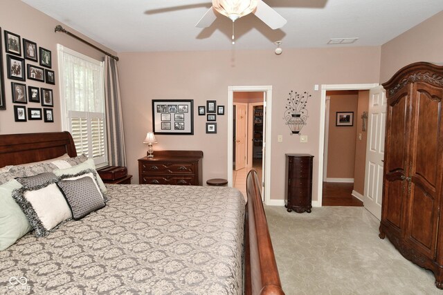 bedroom featuring a ceiling fan, visible vents, and light colored carpet