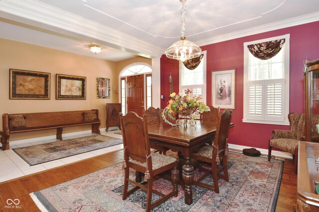 dining area featuring baseboards, ornamental molding, wood finished floors, and a chandelier