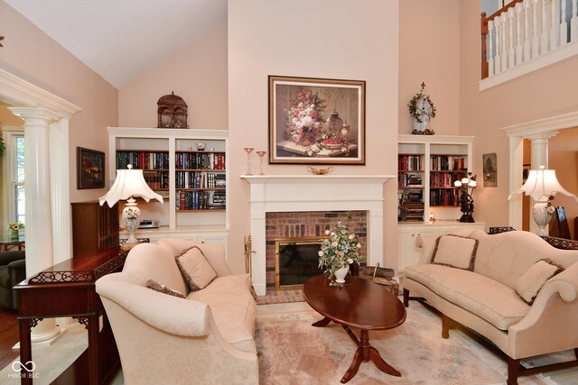living area featuring a fireplace, ornate columns, high vaulted ceiling, and wood finished floors