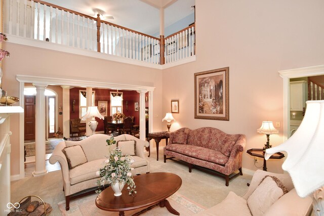 carpeted living room featuring baseboards, a high ceiling, and ornate columns
